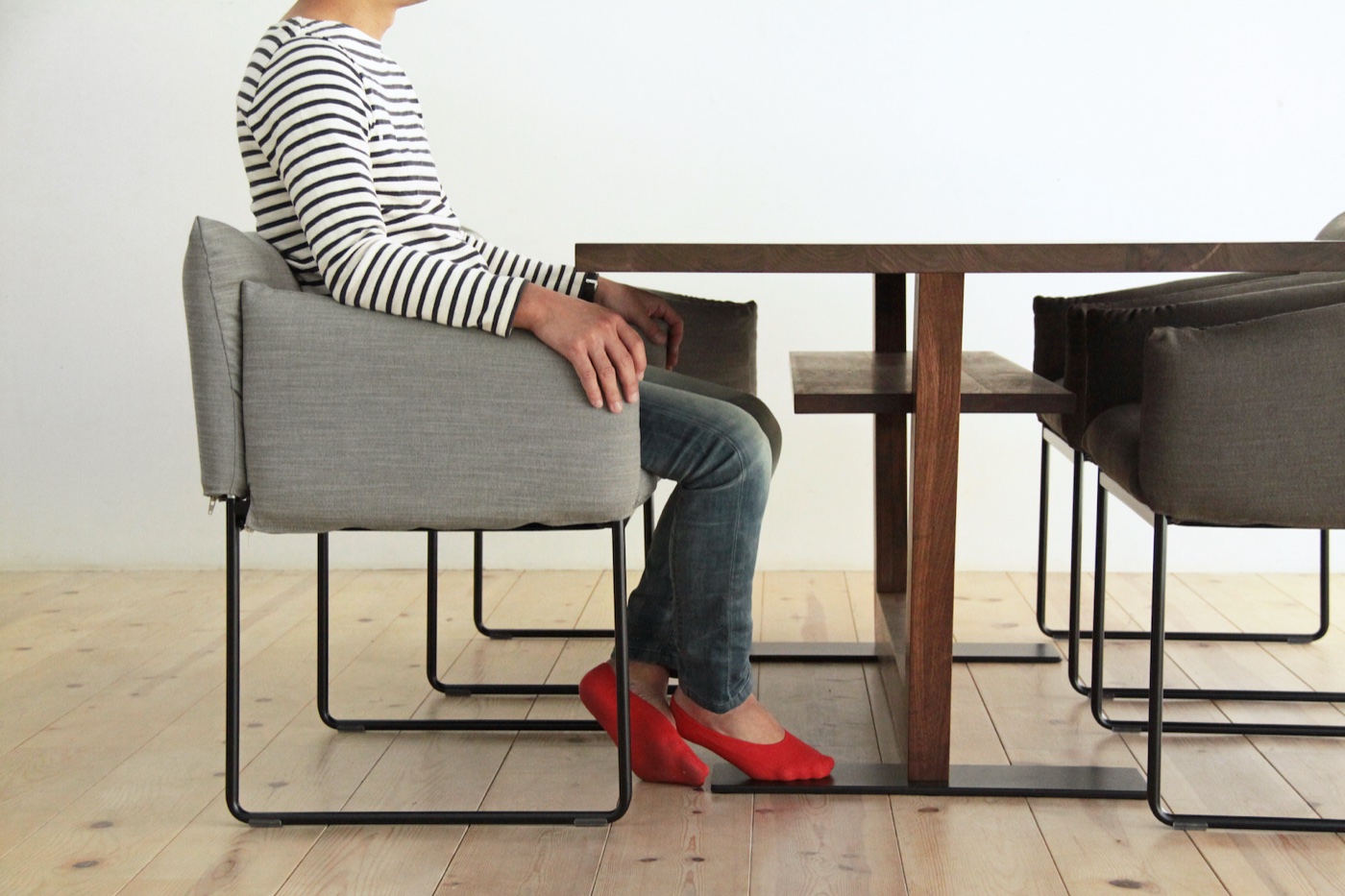 若い男性がウォールナット無垢材テーブルに座り、肘が自然な90度の角度に収まる快適な姿勢を横から示したシーン